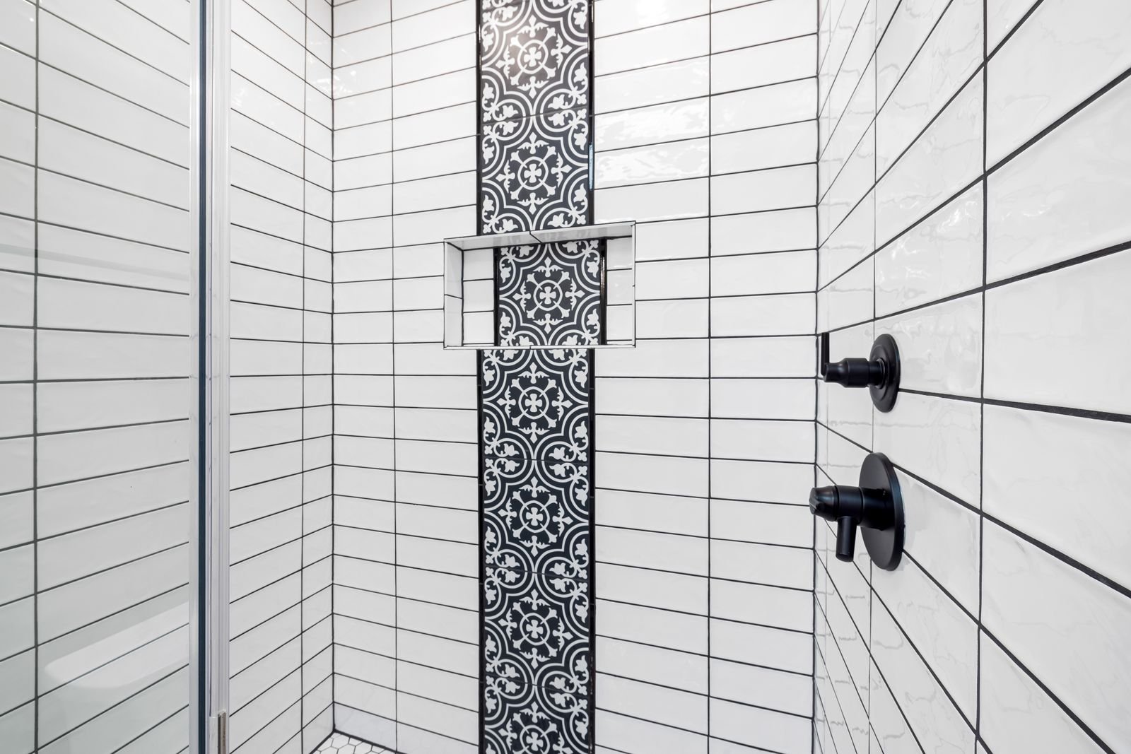 Shower with black and white patterned tile