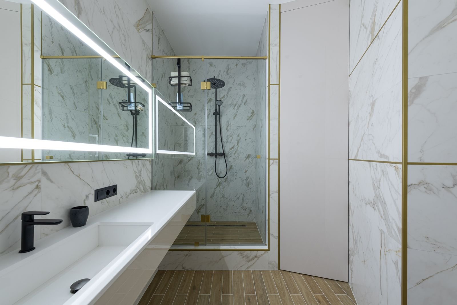 Glass shower and sink in a bathroom with marble tile walls