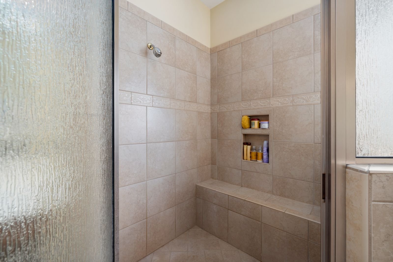Walk-in shower with beige tile and a glass panel
